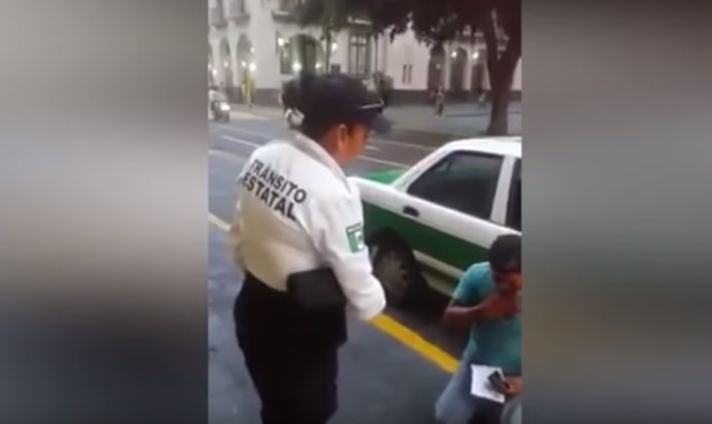 taxista se arrodilla ante policía